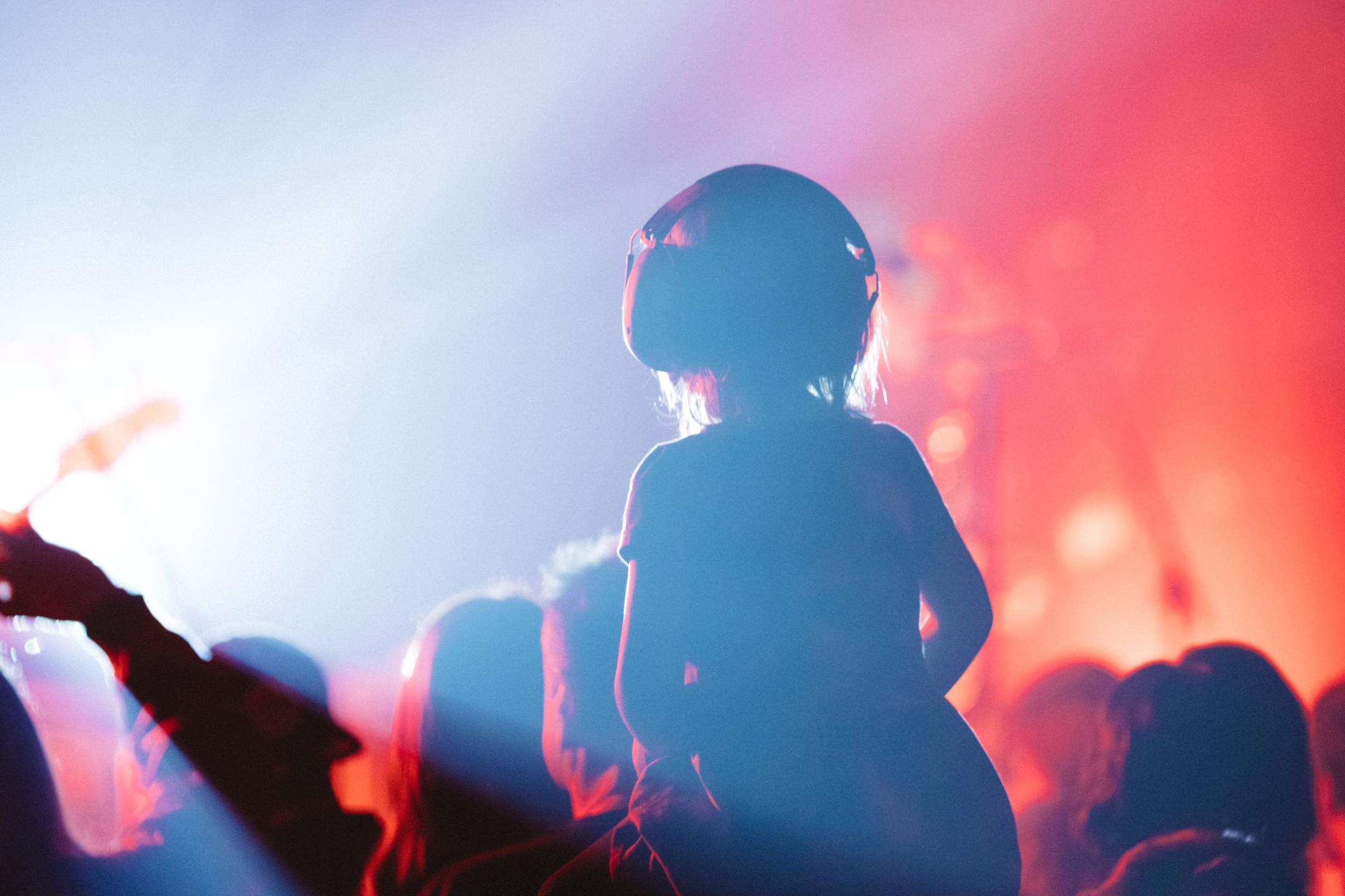 Man sieht einen Menschen mit Kopfhörer auf einem Konzert